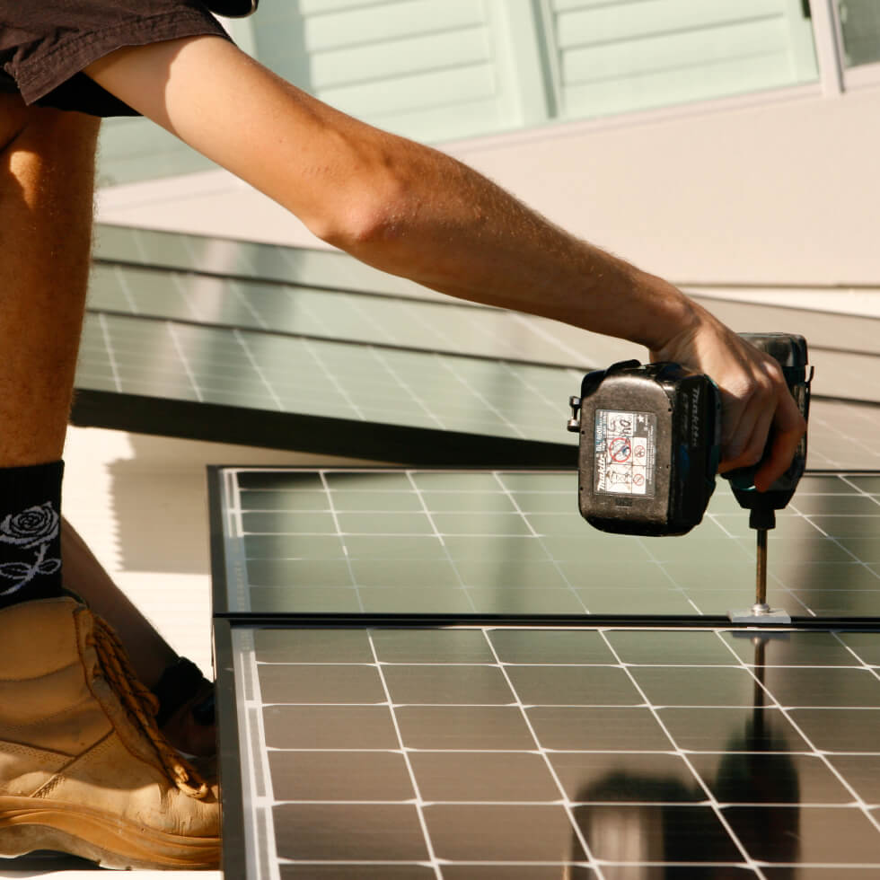A skilled solar installer working with precision, using a drill to install a solar panel in Baringa