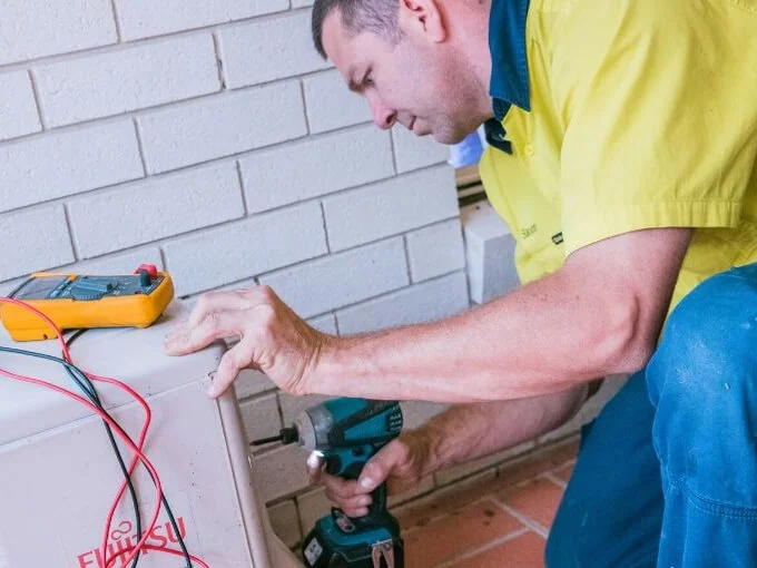 An electrician is working on an air conditioner on the Sunshine Coast.